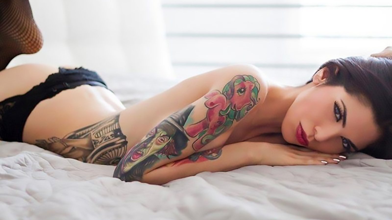 Красивая девушка с татуировками позирует в трусиках